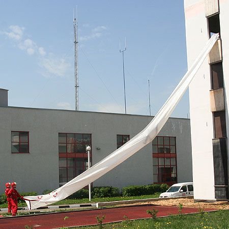 Sloping fire escape chute system deployed at an angle on an industrial structure.